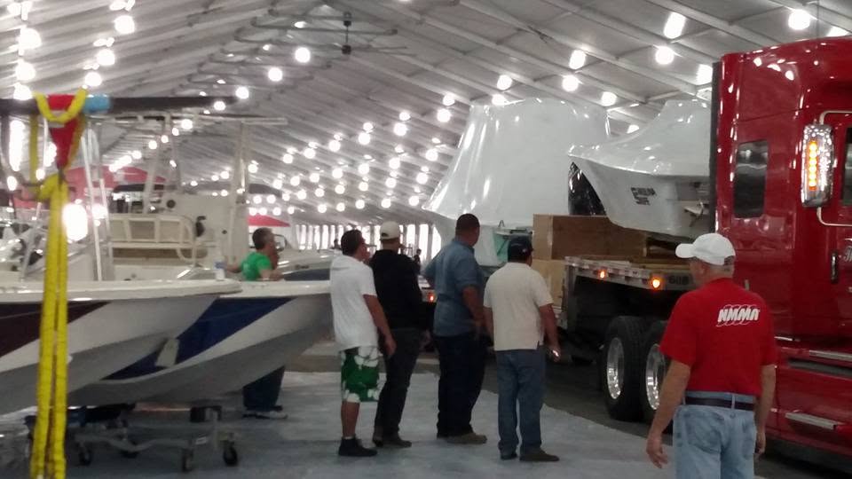 Marine show load-in with boats being moved from transport trucks onto the exhibition floor