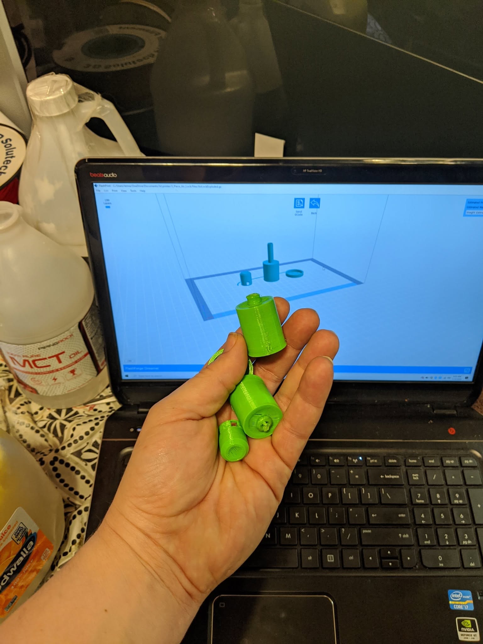 A CAD model on screen beside the physical parts produced from it