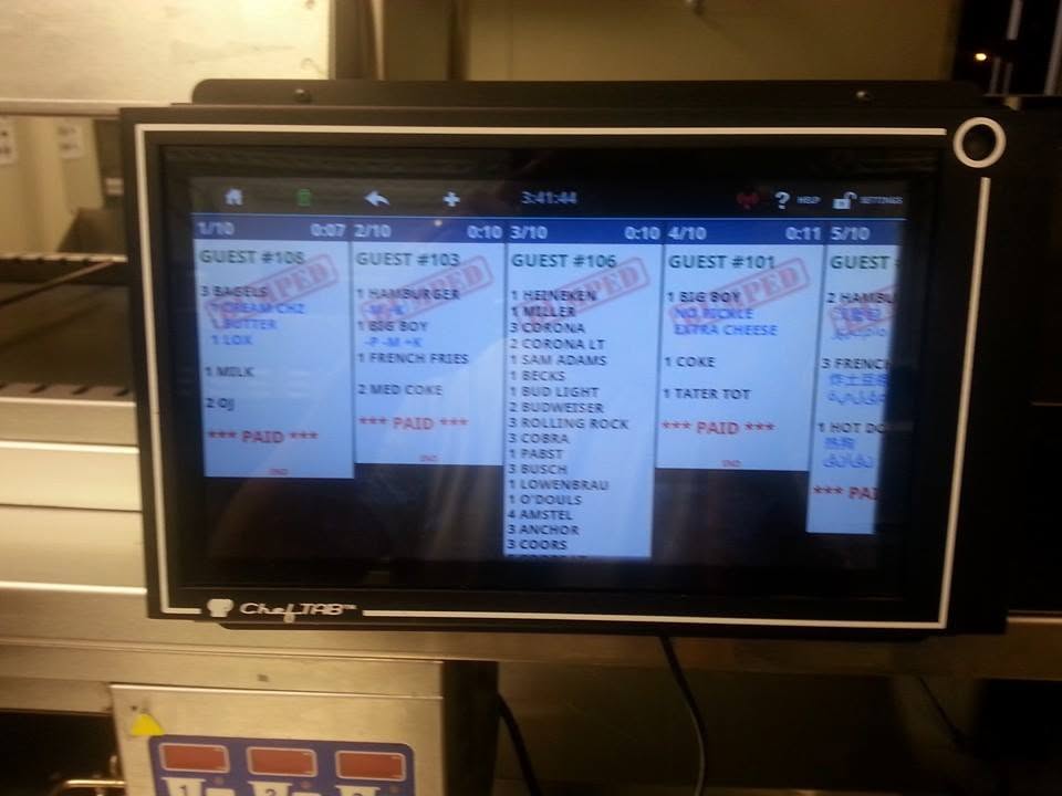 Programmed restaurant order display physically installed above commercial kitchen equipment